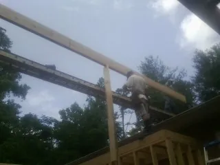 Carpenter setting a ridge beam over a new addition frame — Ice Dam Removal by Roofing Brothers in Ellinwood