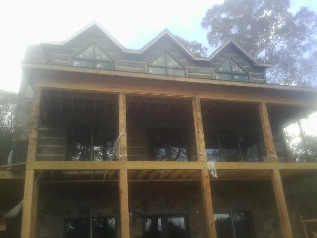 Dormers and porch framing on a large log home under construction — Roof Coating work by our crew in Ellinwood