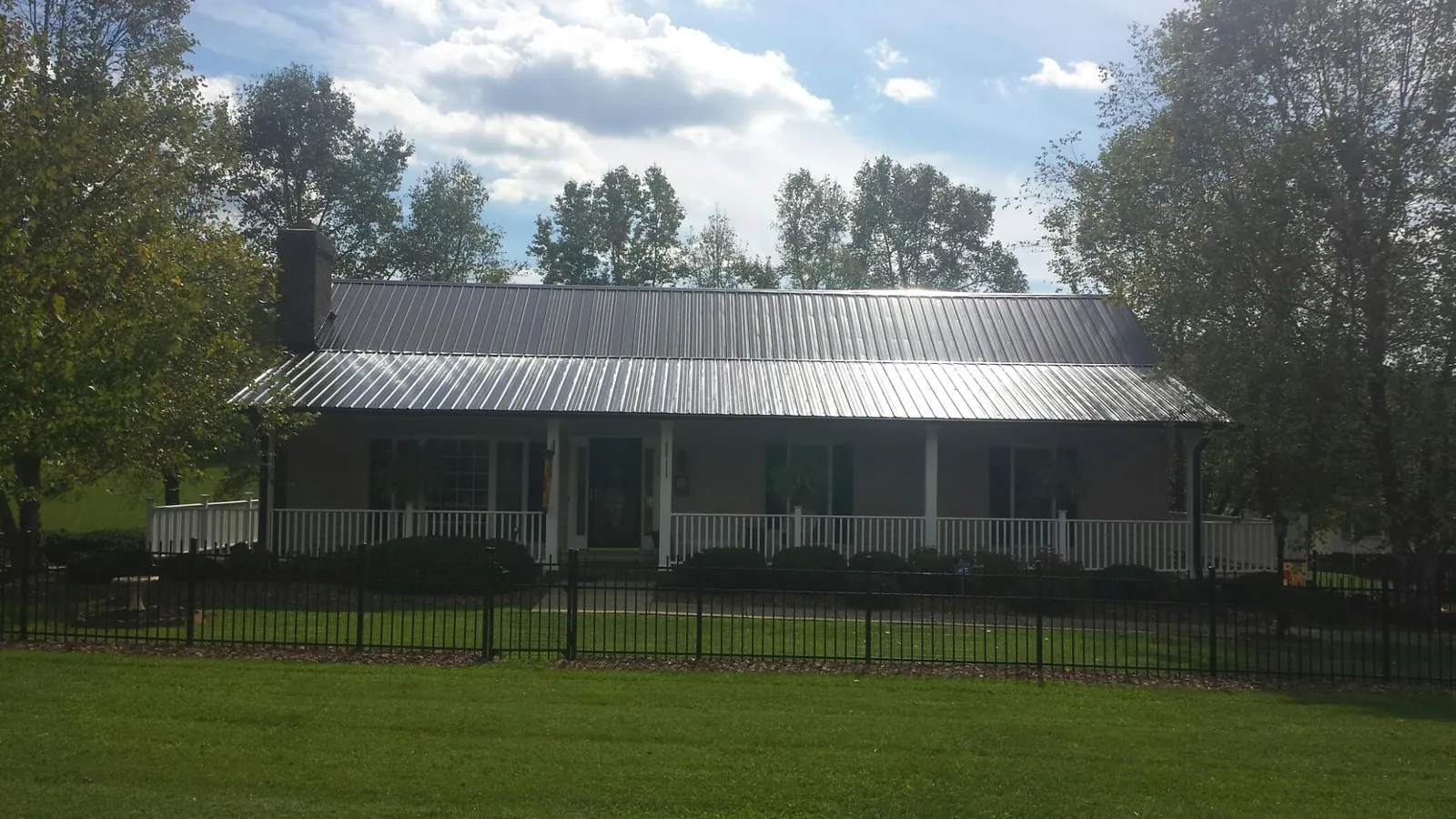 Gray metal roof on a brick ranch with a full width front porch — Gutter Guard Installation work by our crew in Ellinwood
