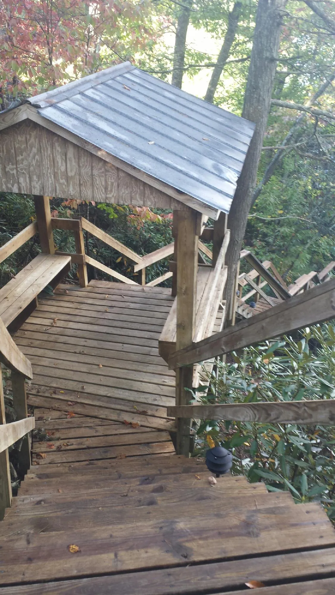 Metal roofed shelter over wooden steps on a wooded walkway — Skylight Repair & Installation work by our crew in Ellinwood