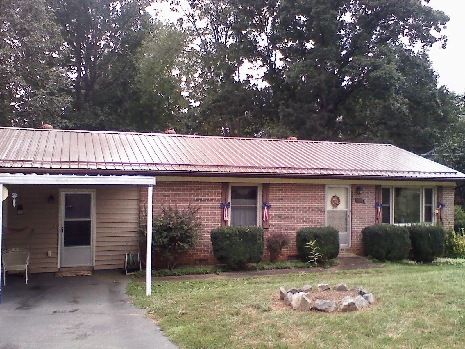 Bronze metal roof and carport on a brick ranch home — Roof Repair work by our crew in Ellinwood
